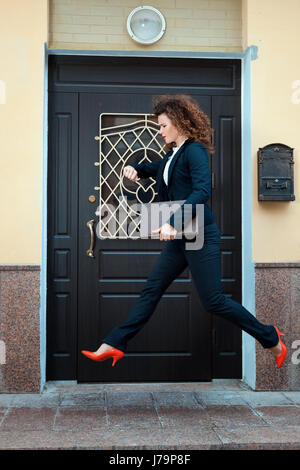 Girl in a pantsuit runs in a hurry. She runs through the city streets. Stock Photo