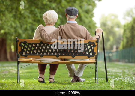 Rear view shot of a senior couple sitting on a wooden bench in the park Stock Photo