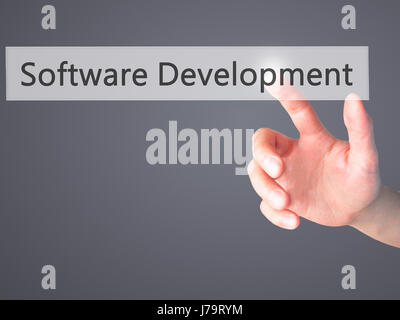 Software Development - Hand pressing a button on blurred background concept . Business, technology, internet concept. Stock Photo Stock Photo