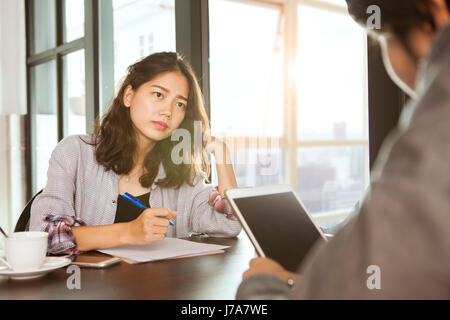 working asian woman team meeting with serious problem on office working table Stock Photo