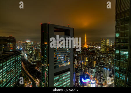 Nightfall in Tokyo with all the bright city lights. The alignment of the Tokyo Tower and the setting sun creates harmony between city and nature. Stock Photo
