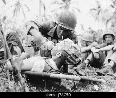 Navy corpsman gives drink to a wounded Marine in Guam, 1944. Stock Photo