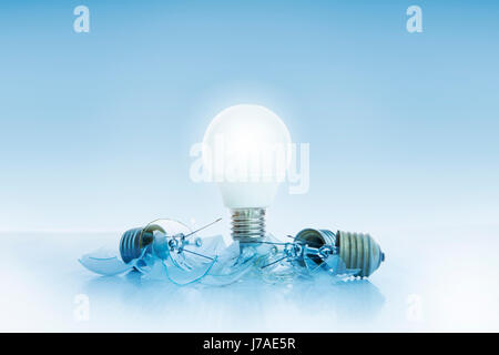 abstract of led light bulb glowing on light blue background with another broken on ground use for idea and creative symbol Stock Photo