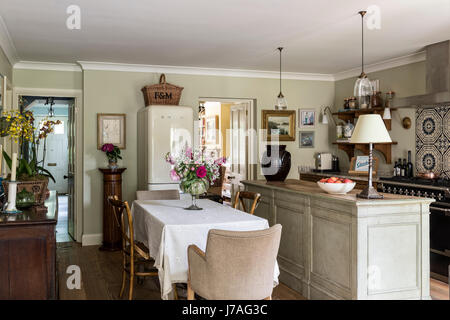 Elegant traditional feeling kitchen with antique dining table and chairs, Smeg fridge and butchers island. The pendant lights are from Hector Finch Stock Photo