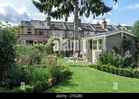 Summerhouse in english garden with wicker furniture and tidy lawns Stock Photo