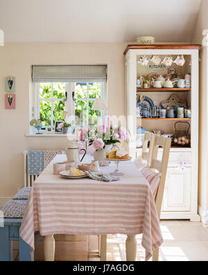 Striped table cloth in pretty country kitchen with ticking stripe blinds by Ian Mankin Stock Photo