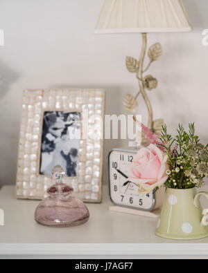 Detail of bedside table with alarm clock, framed photograph and posey of flowers Stock Photo