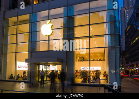 Apple Store Fifth Avenue Exterior With Shoppers Inside At Dusk, Manhattan, New York, USA Stock Photo