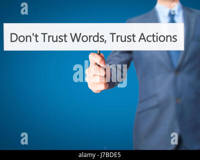 Don't Trust Words, Trust Actions - Businessman hand holding sign. Business, technology, internet concept. Stock Photo Stock Photo