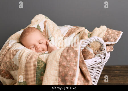 Infant boy with closed eyes. Cute kid touching his face. Baby skin care tips. Stock Photo