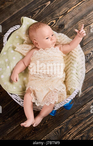 Little kid pointing finger. Child in basket, top view. Baby sign language. Stock Photo