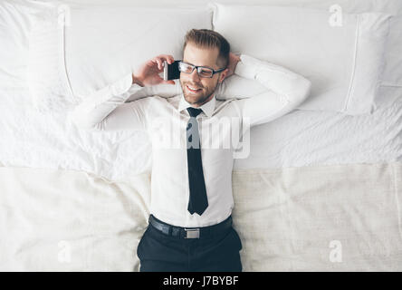 Top view. Young handsome businessman with glasses lying on the bed Stock Photo