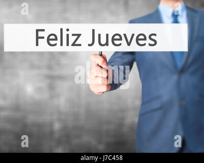 Feliz Jueves (Happy Thursday In Spanish)  - Businessman hand holding sign. Business, technology, internet concept. Stock Photo Stock Photo