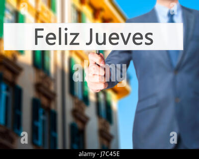 Feliz Jueves (Happy Thursday In Spanish)  - Businessman hand holding sign. Business, technology, internet concept. Stock Photo Stock Photo