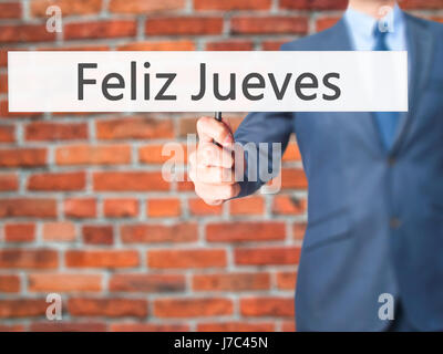 Feliz Jueves (Happy Thursday In Spanish)  - Businessman hand holding sign. Business, technology, internet concept. Stock Photo Stock Photo