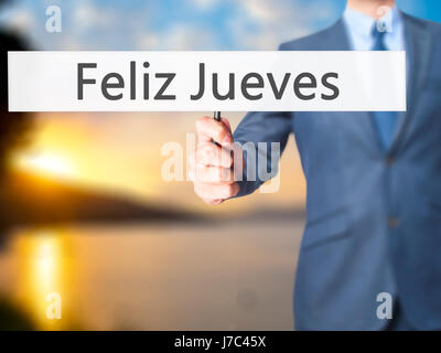 Feliz Jueves (Happy Thursday In Spanish)  - Businessman hand holding sign. Business, technology, internet concept. Stock Photo Stock Photo