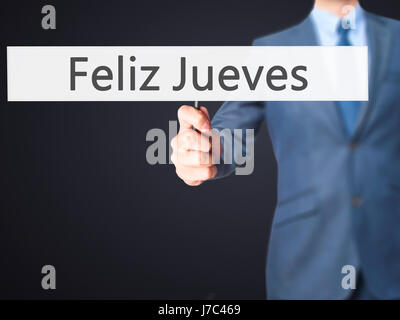 Feliz Jueves (Happy Thursday In Spanish)  - Businessman hand holding sign. Business, technology, internet concept. Stock Photo Stock Photo