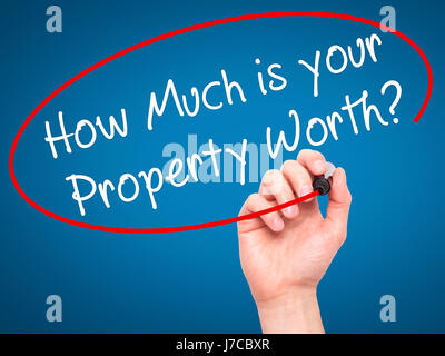 Man Hand writing How Much is your Property Worth? with black marker on visual screen. Isolated on blue. Business, technology, internet concept. Stock  Stock Photo