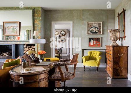 Leopard print chair at antique desk with large mirror above fireplace and Designers Guild Cassia chair Stock Photo