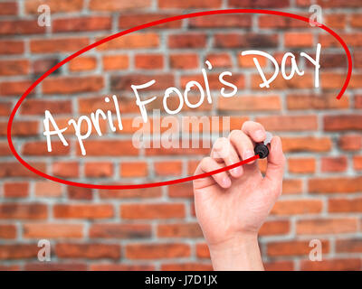 Man Hand writing April Fool's Day with black marker on visual screen. Isolated on bricks. Business, technology, internet concept. Stock Photo Stock Photo