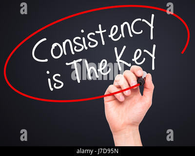 Man Hand writing Consistency is The Key with black marker on visual screen. Isolated on black. Business, technology, internet concept. Stock Photo Stock Photo