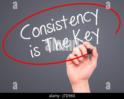 Man Hand writing Consistency is The Key with black marker on visual screen. Isolated on grey. Business, technology, internet concept. Stock Photo Stock Photo