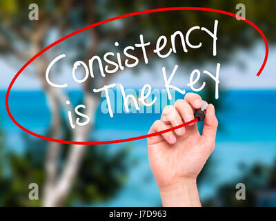 Man Hand writing Consistency is The Key with black marker on visual screen. Isolated on nature. Business, technology, internet concept. Stock Photo Stock Photo