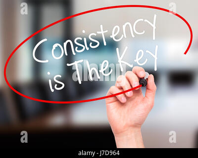 Man Hand writing Consistency is The Key with black marker on visual screen. Isolated on office. Business, technology, internet concept. Stock Photo Stock Photo