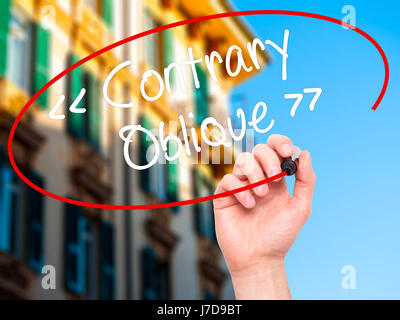 Man Hand writing Contrary - Oblique with black marker on visual screen. Isolated on background. Business, technology, internet concept. Stock Photo Stock Photo