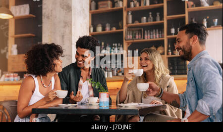 Young people sitting at a coffee shop and talking. Group of friends having coffee together in a cafe. Stock Photo