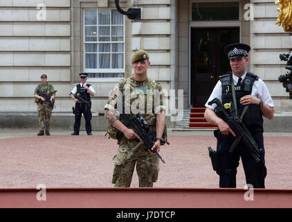 Members of the army join police officers outside Buckingham Palace, London, after Scotland Yard announced armed troops will be deployed to guard 'key locations' such as Buckingham Palace, Downing Street, the Palace of Westminster and embassies. Stock Photo