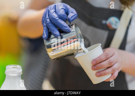Close-up of barista hands, preparing proper cappuccino pouring Milk with foam into cup of coffee. Preparation for creating a pattern. Concept of tasty aroma coffee Stock Photo