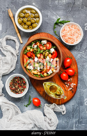 Spring vegetable salad with arugula, cherry tomatoes, chickpeas, olives and feta cheese. Healthy, vegan, detox food. Top view Stock Photo