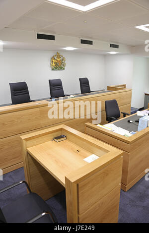 Interior of a modern, English courtroom. Shows judges/magistrates bench and witness box (with Bible) in the foreground Stock Photo