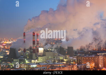 Steam and smoke from the chimneys and cooling towers city Central Heating and Power Plant. The view from the heights in the twilight, winter Stock Photo