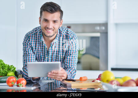Happy man using digital tablet in kitchen at home Stock Photo
