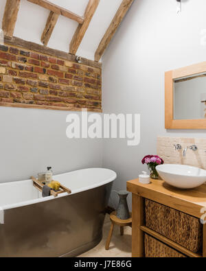 Freestanding bath in rustic bathroom with exposed brick wall. The walls are painted in Light Grey by Albany Stock Photo