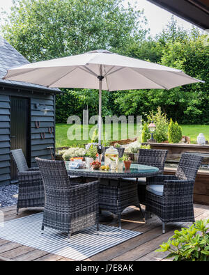 Outdoor furniture under parasol in elegant garden Stock Photo