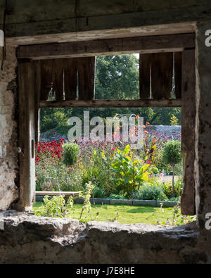 View through rustic barn window to  walled garden Stock Photo