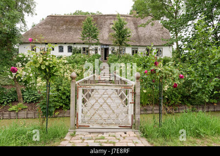 Gated footbridge access to garden of thatched 17th century famhouse built on 12th century earthmound to prevent flooding Stock Photo