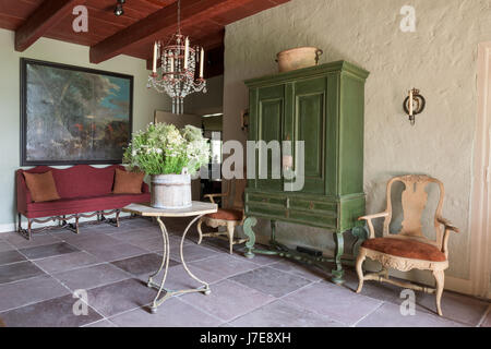 Green painted Swedish cupboard and cafe table, with French mid-19th century glass chandelier Stock Photo