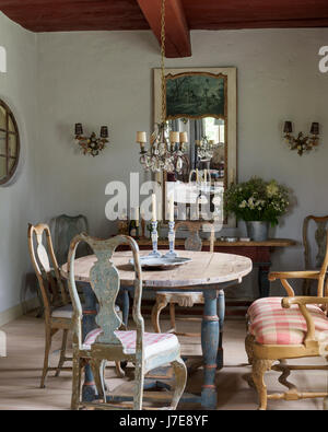 French 'trummeau' mirror above antique sideboard with 18th century Swedish chairs and crystal and gilt French chandelier Stock Photo