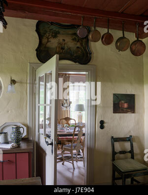 Copper pots hang above open doorway in farmhouse kitchen Stock Photo