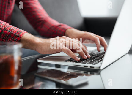 Close up of young man typing on keyboard of laptop at home Stock Photo