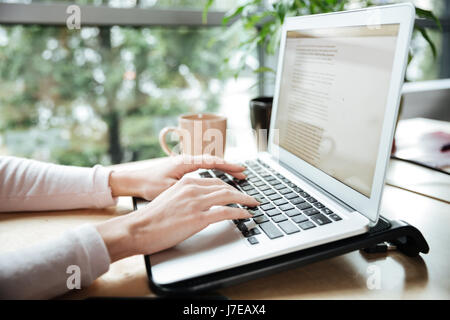 Cropped photo of young woman in office coworking while using laptop computer. Stock Photo