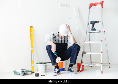 Young tired builder sleeping near repair equipment isolated Stock Photo