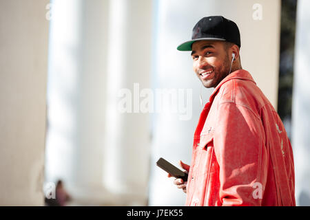 Portrait of a happy stylish afro american man listening to music outdoors on a street Stock Photo