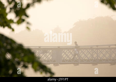 Person crossing the suspension bridge over the River Dee in Chester on a very foggy, misty morning in summer Stock Photo