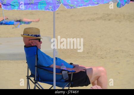 Lyme Regis, Dorset, UK. 25th May, 2017. This man enjoys the shade in Lyme Regis as bright sunshine and climbing temperatures point to a sunny bank holiday weekend. Credit: Tom Corban/Alamy Live News Stock Photo