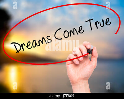 Man Hand writing Dreams Come True with black marker on visual screen. Isolated on nature. Business, technology, internet concept. Stock Photo Stock Photo